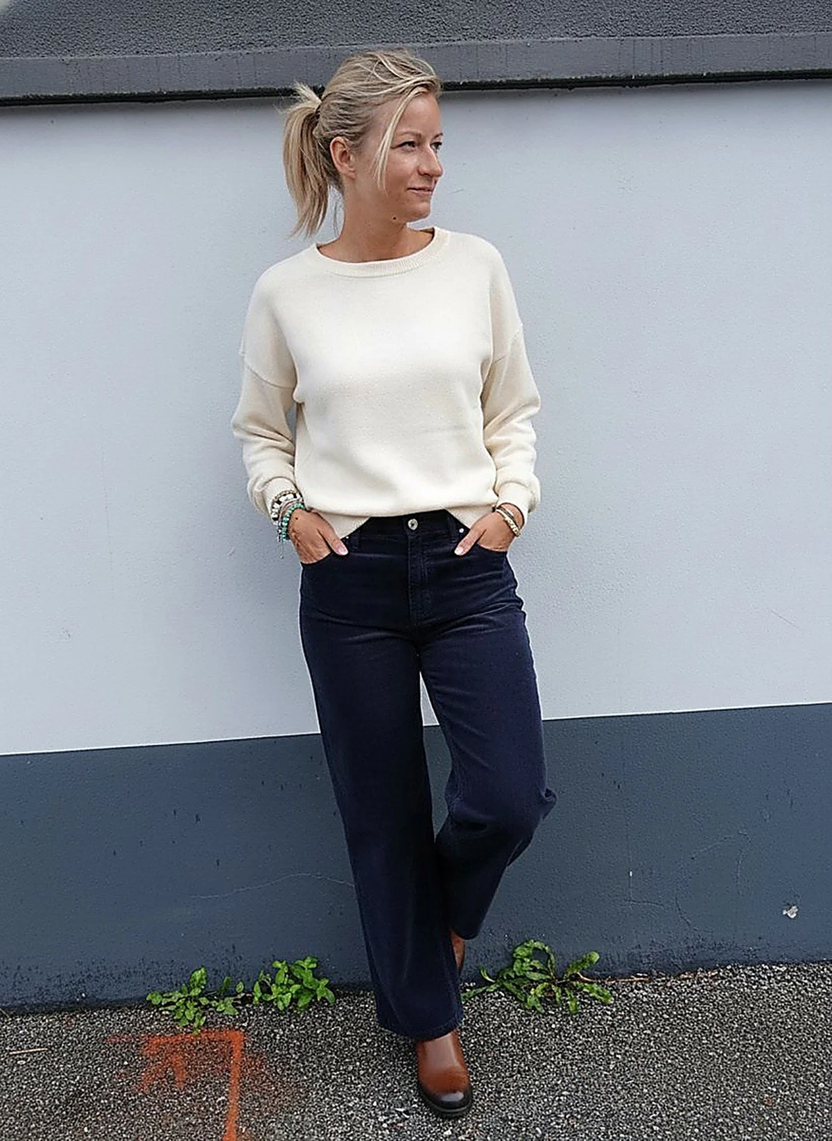 Laurie en pantalon Caitlina fine côte, adossée au mur de la boutique