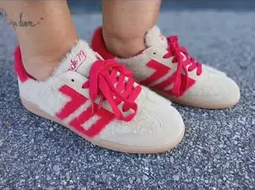 Baskets fourrées crème à bandes rouges, portées sur le bitume